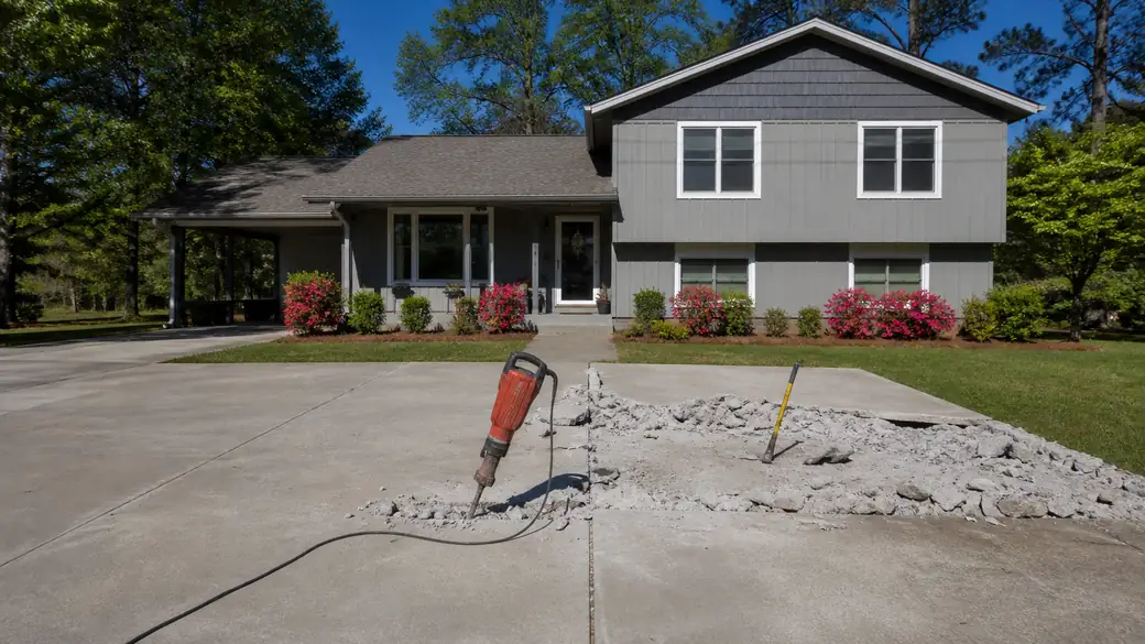 concrete demolition and removal completed by a local contractor at a grey split-level home in Warner Robins, GA, in clear late-morning sun.