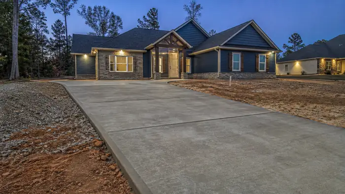 concrete driveway installation completed by a local contractor at a stacked-stone and stucco home in Warner Robins, GA, at blue hour.